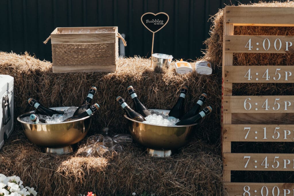 Private Estate Wedding. A tight crop image showing a wedding day timeline with some times for a wedding day, as well as various bottles of wine on ice in a vintage silver cooler.