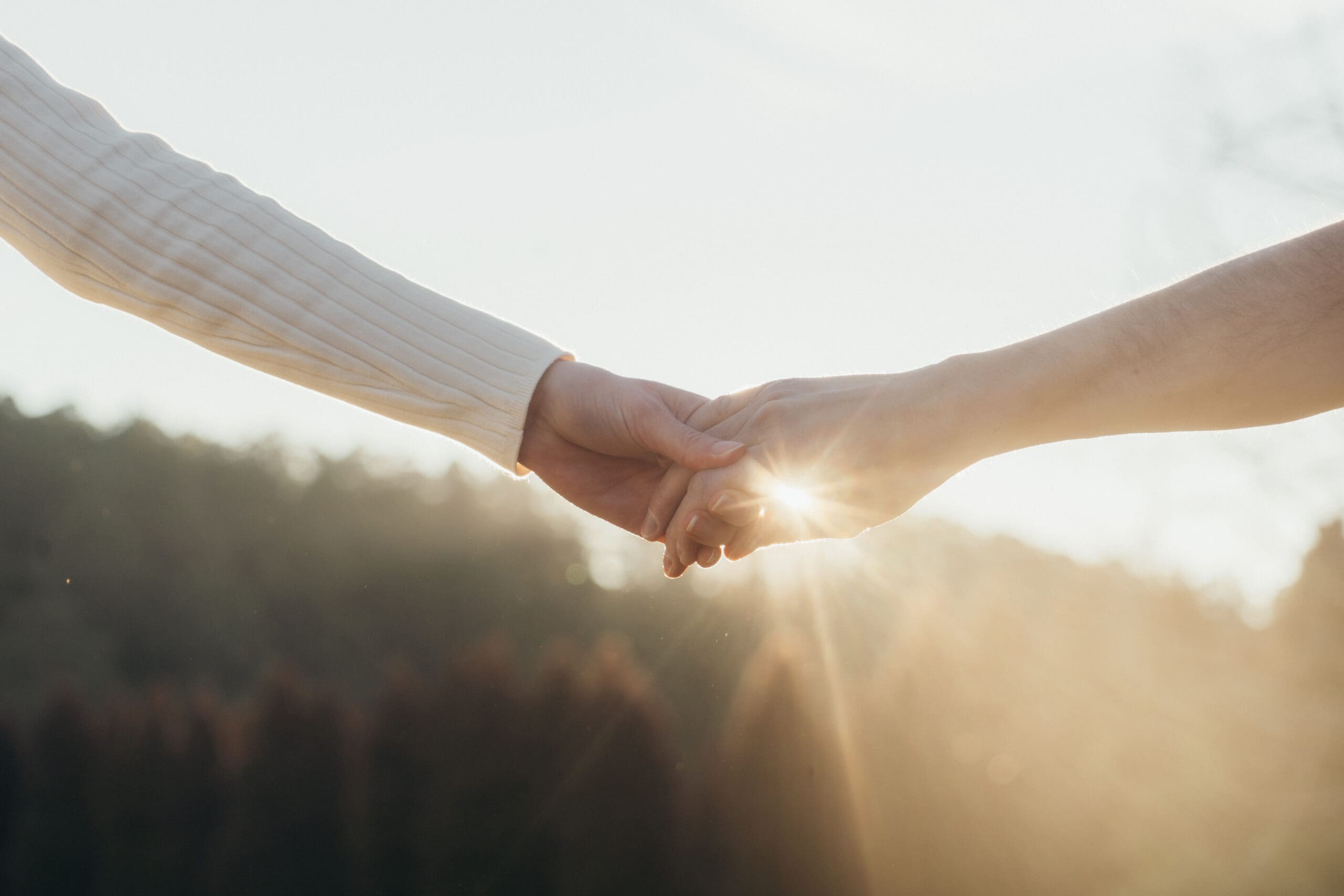 A couple holding hands at golden hour with the sun streaming through