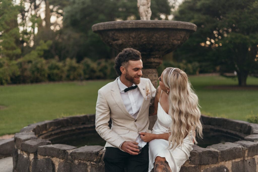Couples portraits at the stone water fountain surrounded by immaculate lawns at Glenfyne Weddings in Gippsland, photo by Ebb and Flow Photography